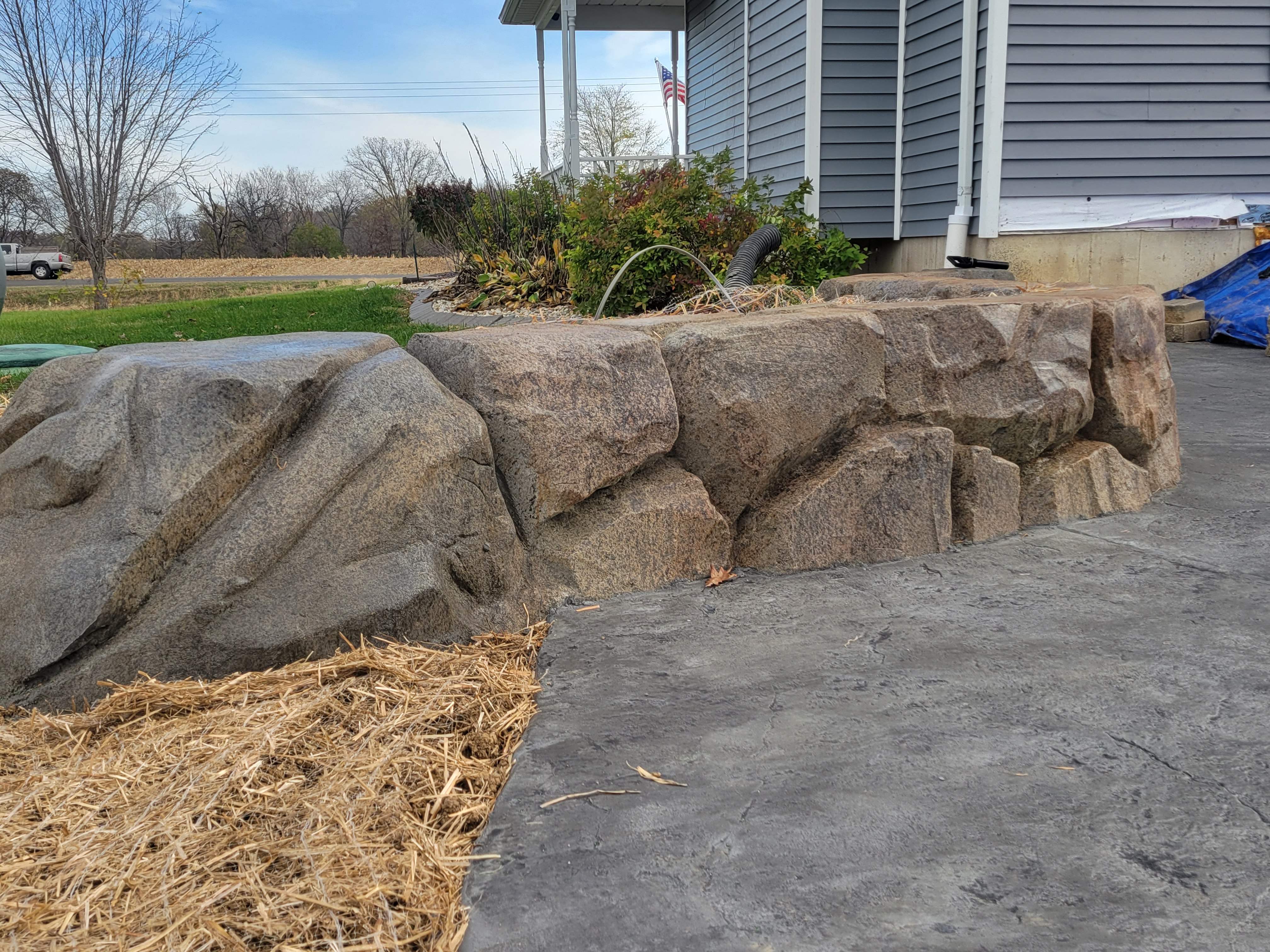 Carved boulder retaining wall beside a stamped patio