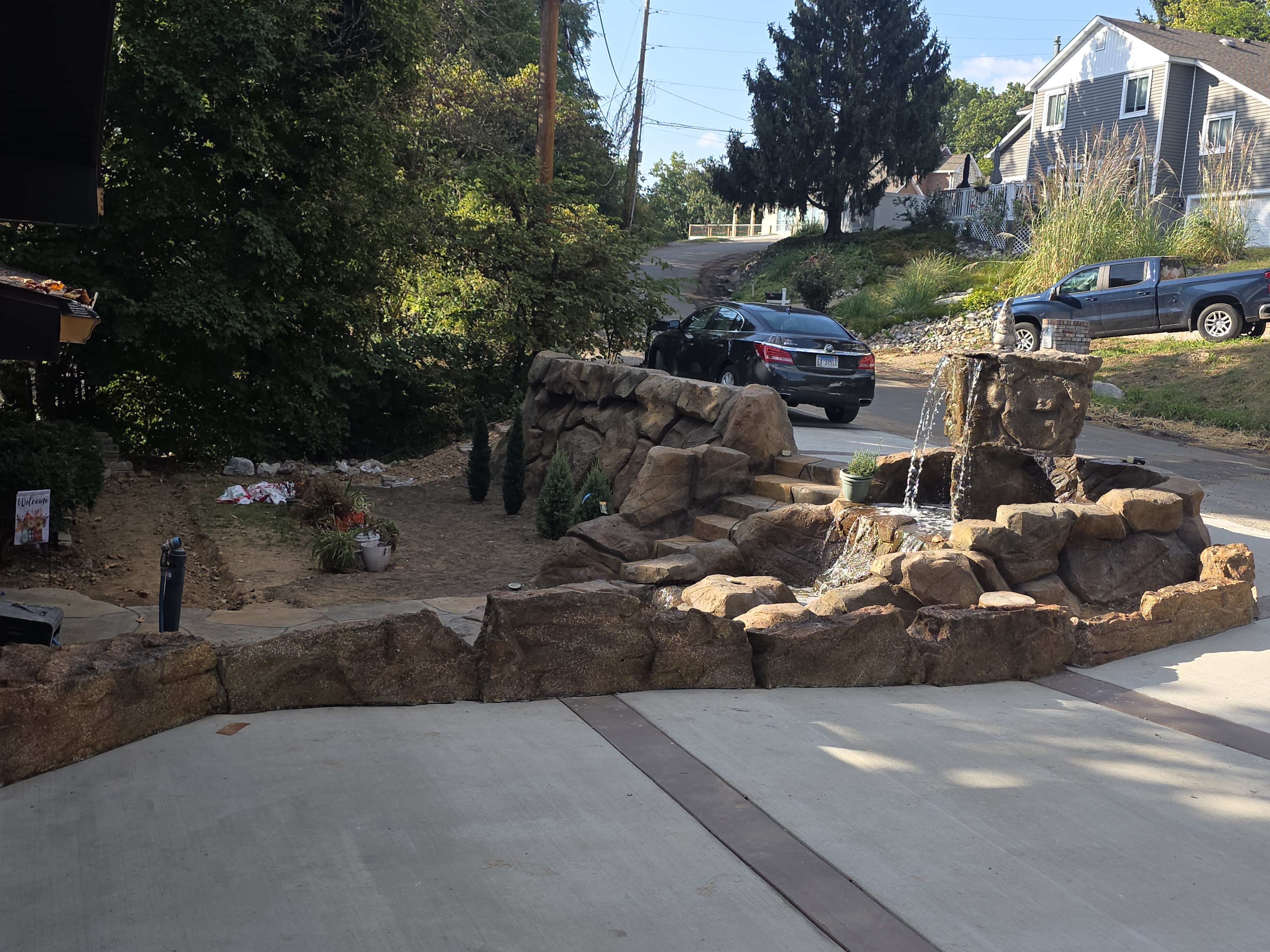 Carved rock retaining wall and waterfall beside a driveway