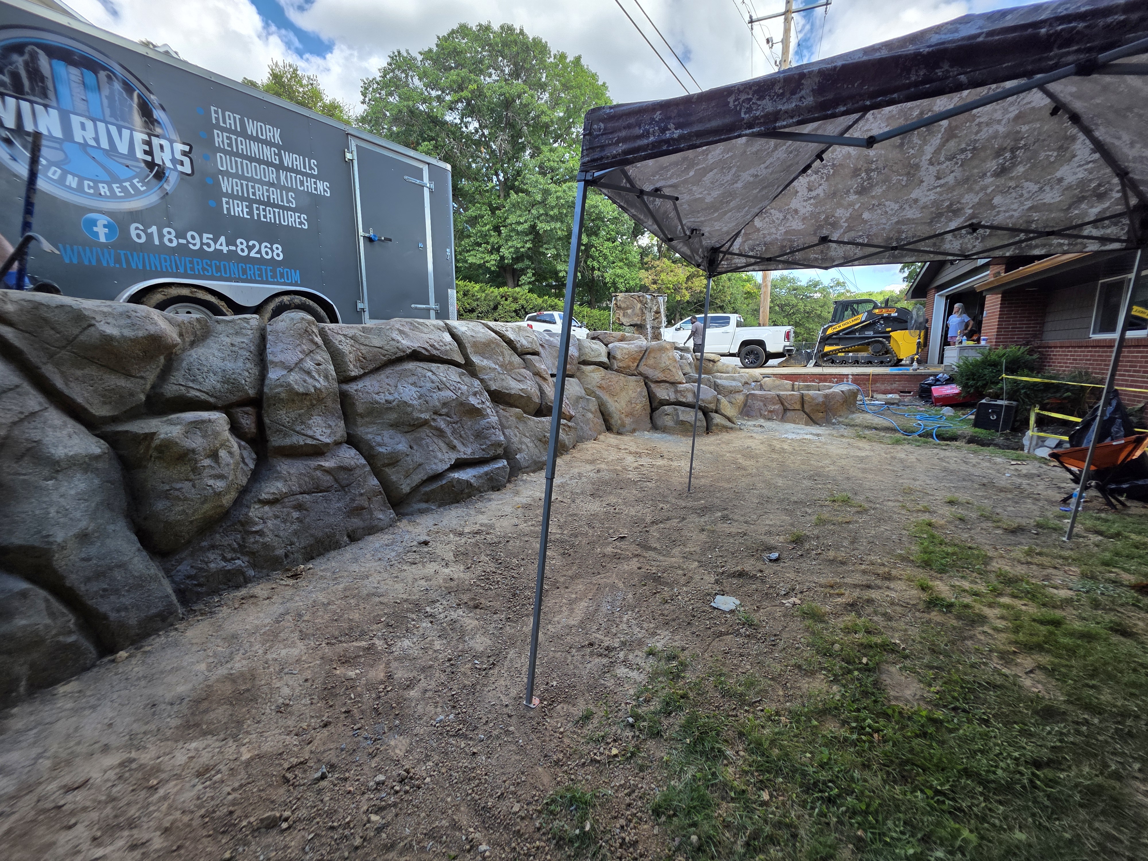 Carved rock retaining wall in progress under a work canopy