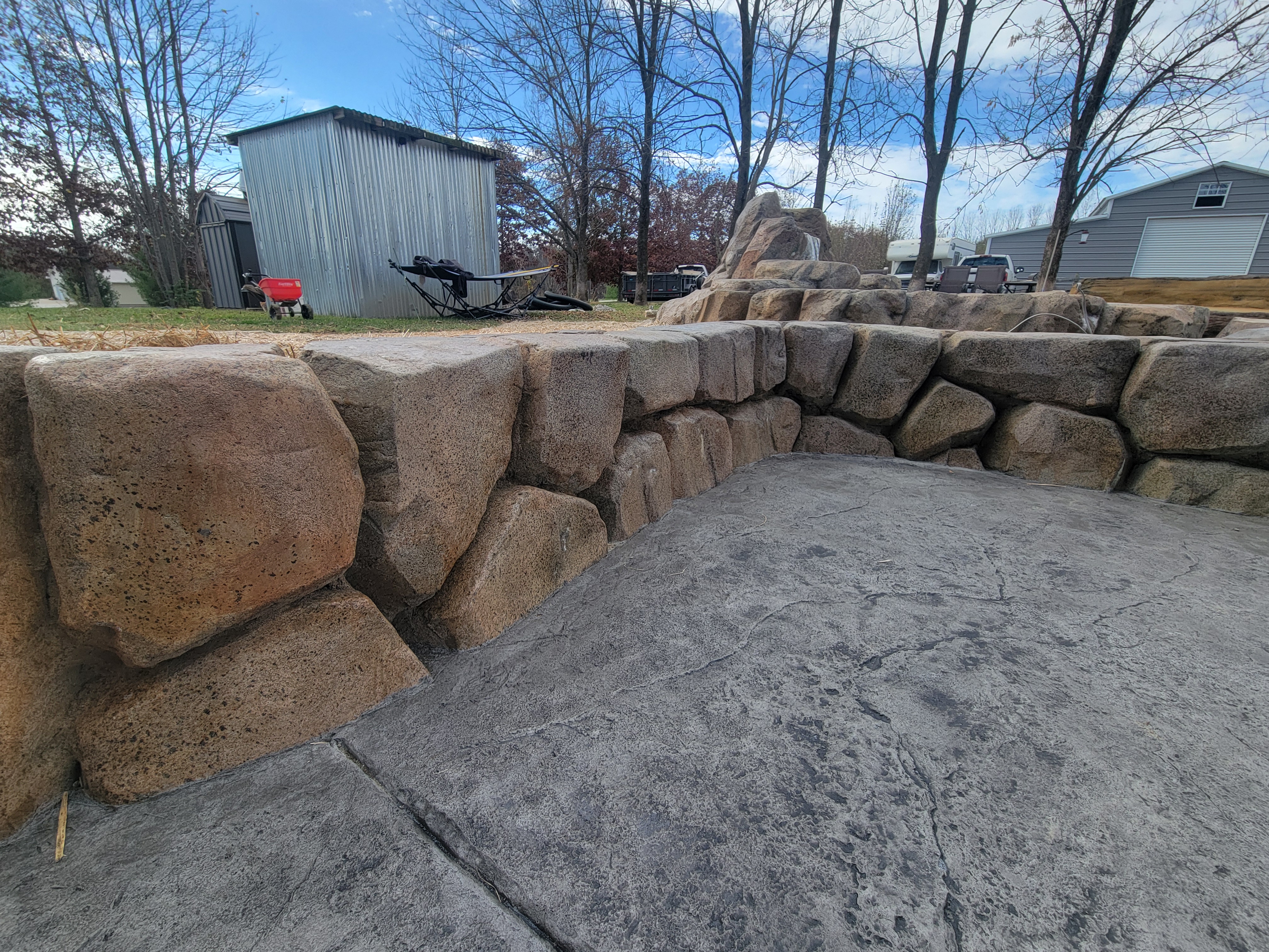 Boulder-style carved concrete wall along a stamped patio