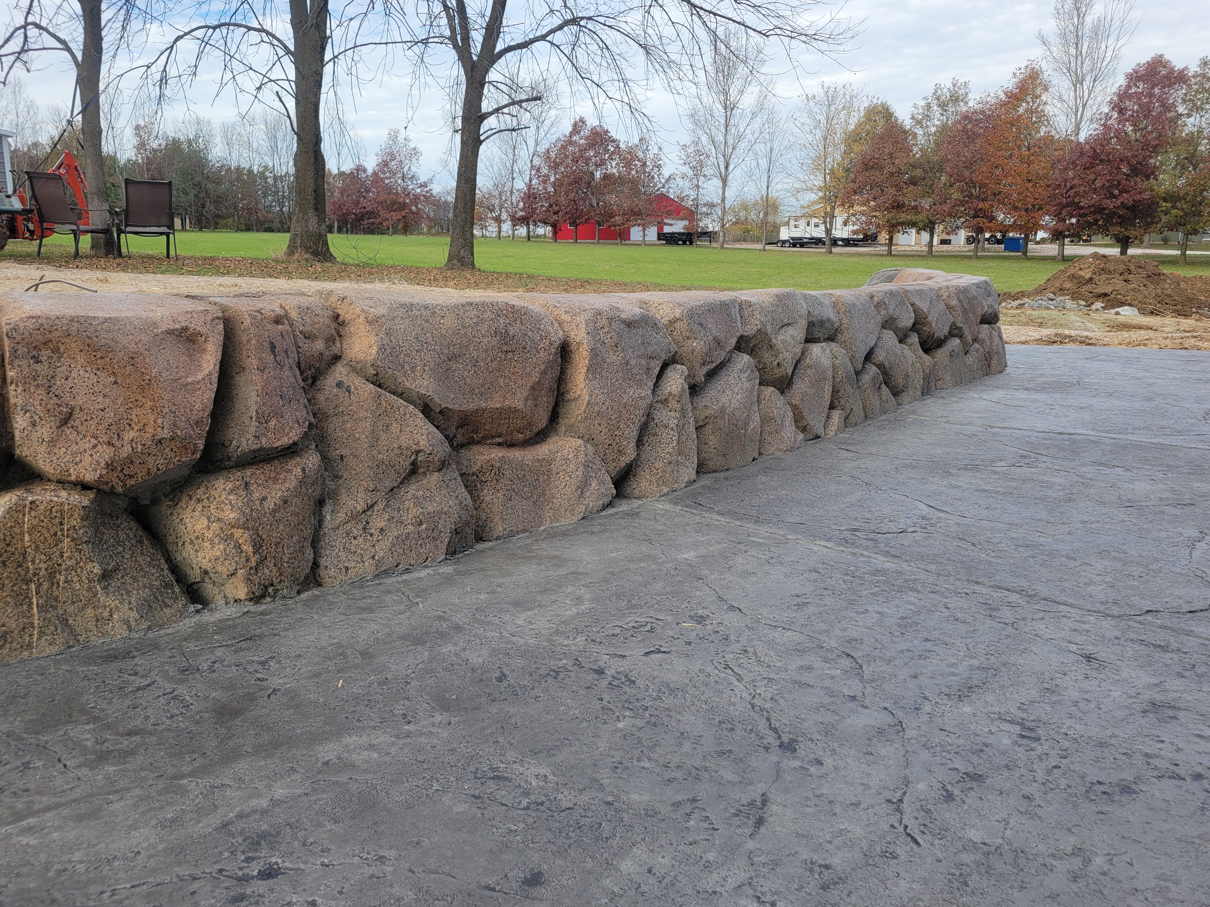 Carved boulder retaining wall along a stamped concrete patio