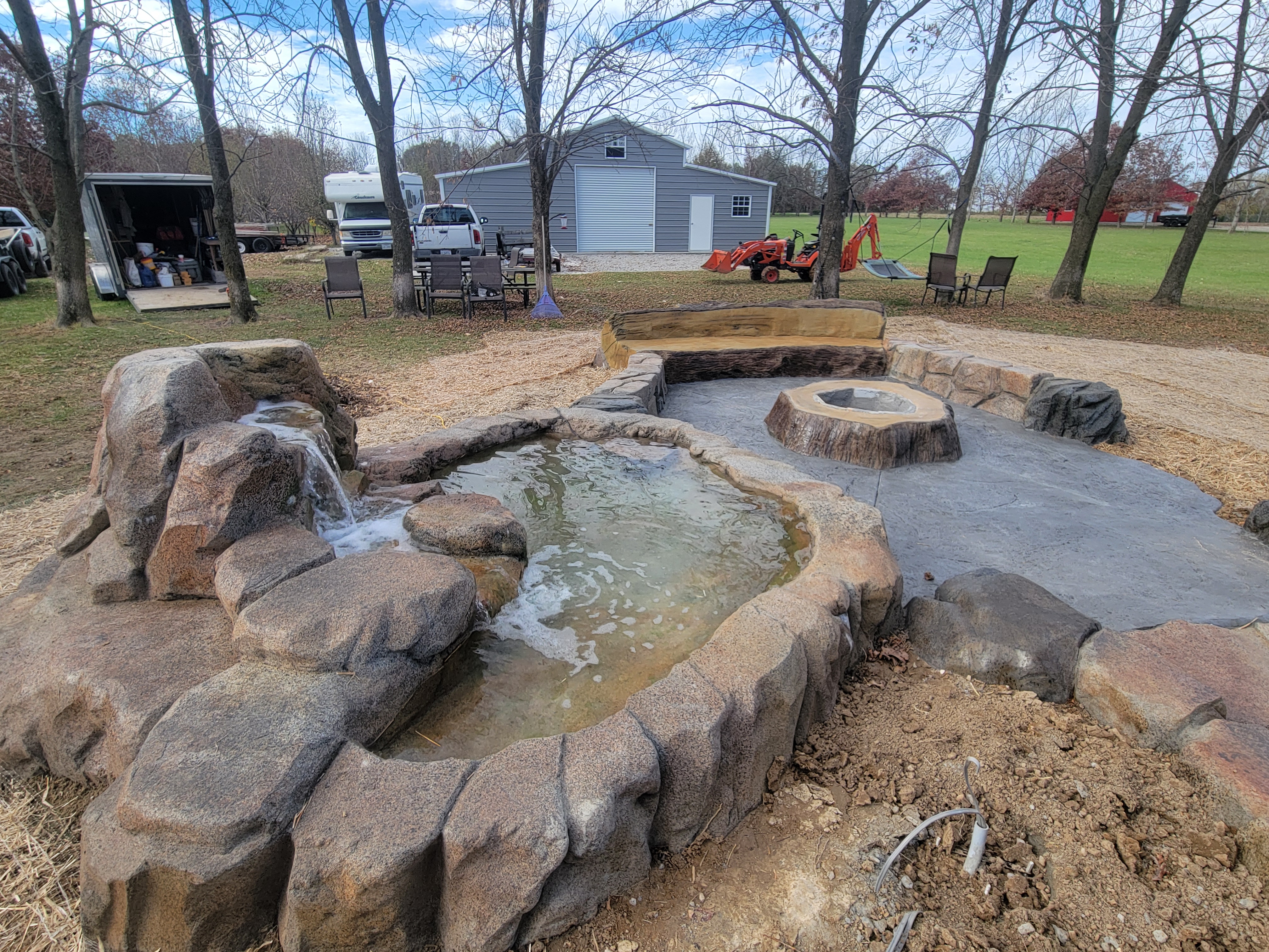 Carved boulder pond and stream beside a fire pit patio