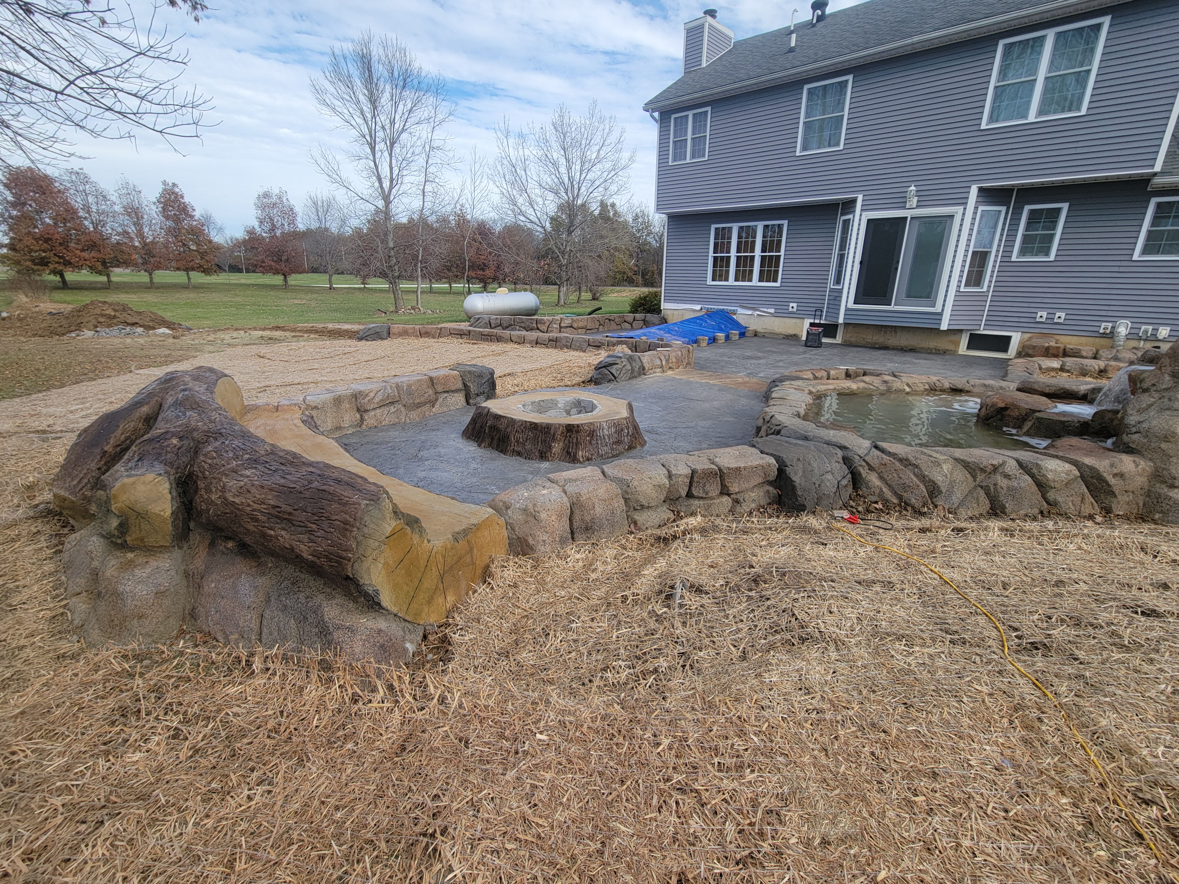 Carved boulder pond edge beside a stamped patio