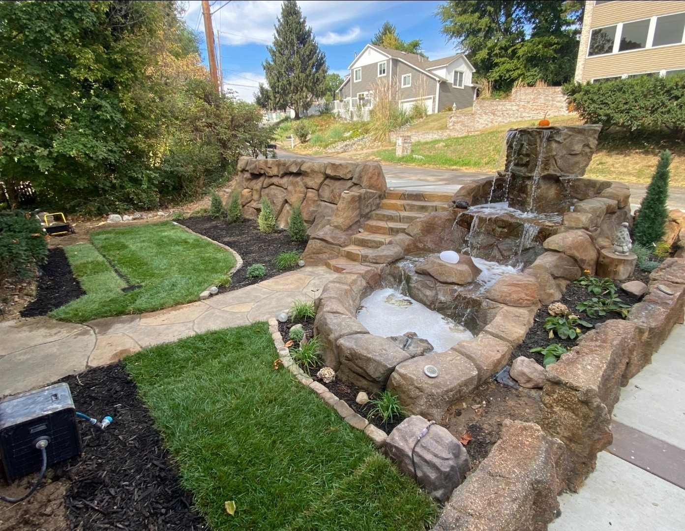 Multi-tier carved rock waterfall along a landscaped walkway